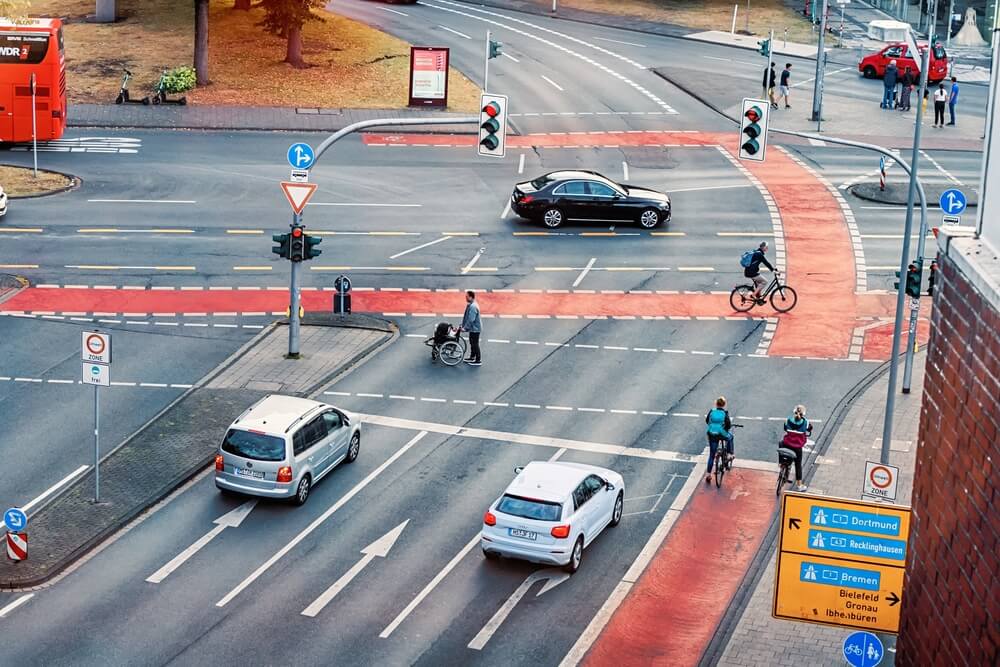 aerial view of city crossroads intersection with dense and busy traffic of cars and cyclists on the bicycle path